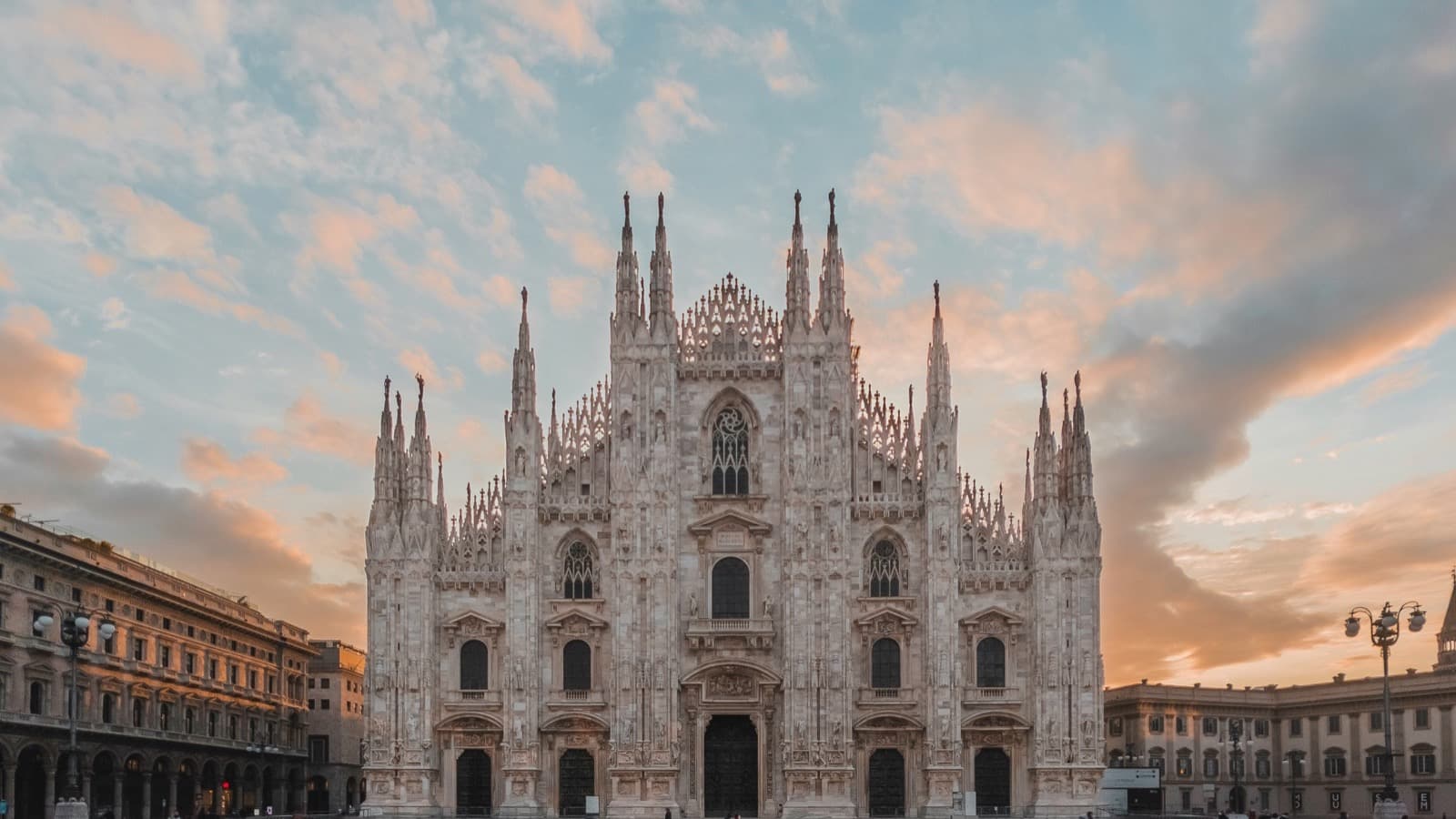 La facciata del Duomo di Milano e la piazza all'alba, con poche persone che camminano